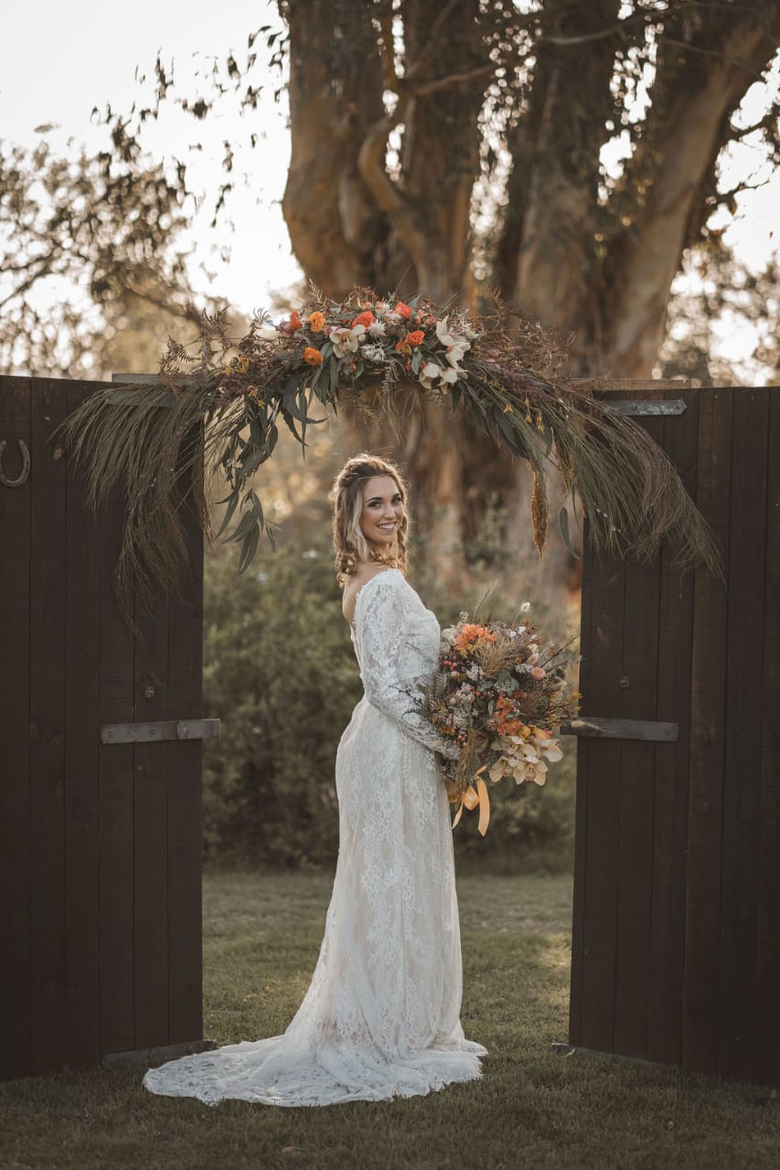 lika This bohemian-inspired wedding gown features a figure-flattering mermaid silhouette, crafted from exquisite Chantilly lace. The elegant V-neckline is framed by long, sheer lace sleeves, adding a touch of romance and sophistication. The back is designed with a captivating low cut, creating an alluring yet refined look. The gown is completed with a delicate short train, perfect for effortless movement while maintaining its ethereal charm.