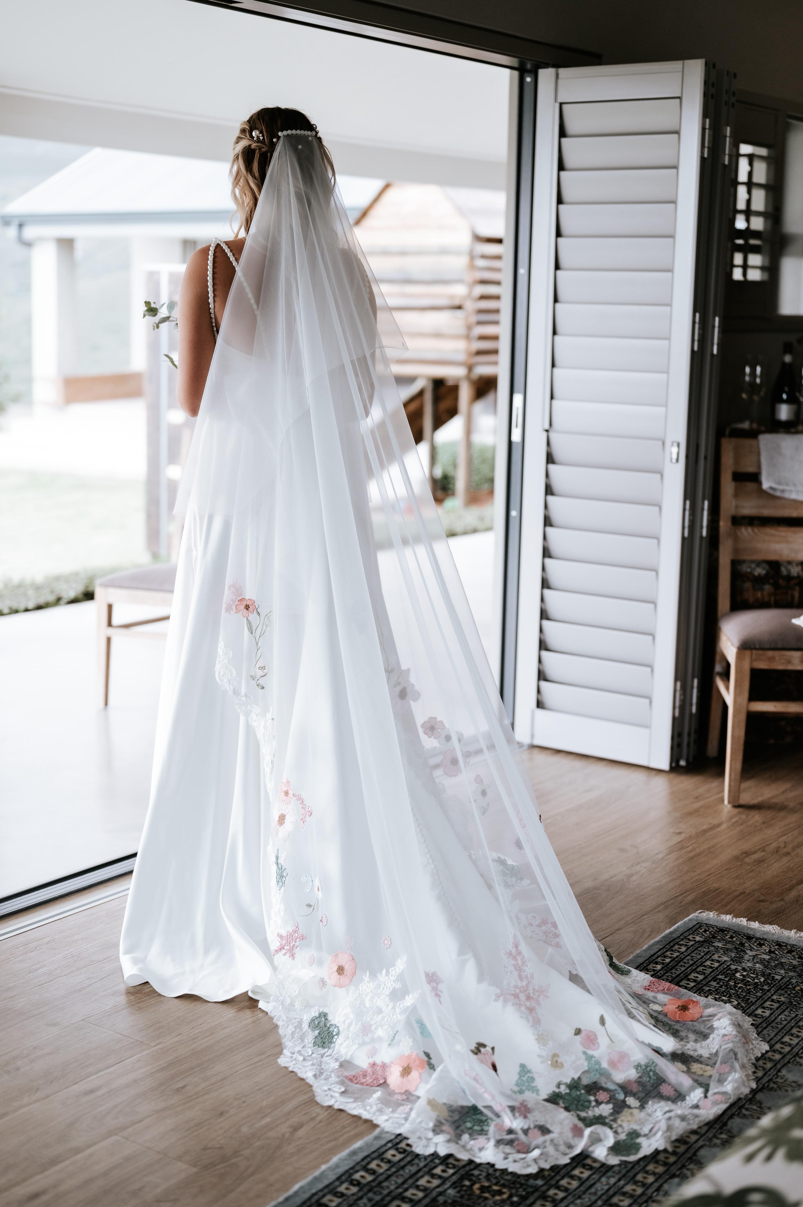 maryke Ruched Satin A-Line Wedding Gown with Pearl Strap Detail  The Maryke gown is a graceful fusion of classic satin elegance and modern detailing. With its soft scoop neckline and romantic ruching, this design flatters the figure while highlighting feminine charm. Pearl-beaded straps add a timeless, luxurious touch, while the open back creates a striking silhouette from behind.  ✨ Design Highlights: ✔ Scoop Neckline with Ruched Satin Bodice – Soft, flattering ruching that contours beautifully to the bust and waist. ✔ Delicate Pearl Straps – A refined accent that adds just the right touch of glam and bridal shimmer. ✔ Low Open Back Bodice – Modern and bold, balanced by the softness of the front. ✔ Nude Tulle Side Inserts – Lightly sheer panels under the arms for added comfort and subtle allure. ✔ Full-Flare A-Line Skirt with Pockets – A romantic and structured silhouette that allows for both elegance and ease. ✔ Long Flowing Train – Adds breathtaking movement and timeless drama as you walk down the aisle.  💫 Customization Options: ✅ Custom sizing tailored to your body shape ✅ Option to adjust neckline, back height, or trail length ✅ Satin available in off-white or ivory tones ✅ Option to add matching veil or pearl-trimmed accessories  🌸 Maryke is for the bride who dreams of timeless elegance, soft shine, and graceful femininity—perfectly blended in one unforgettable gown. 🌸  📞 Book your custom consultation today! 📧 info@bestersbridal.co.za | 📱 084 268 1354  Satin A-Line • Scoop Neck • Pearl Straps • Low Back • Pockets • Long Train