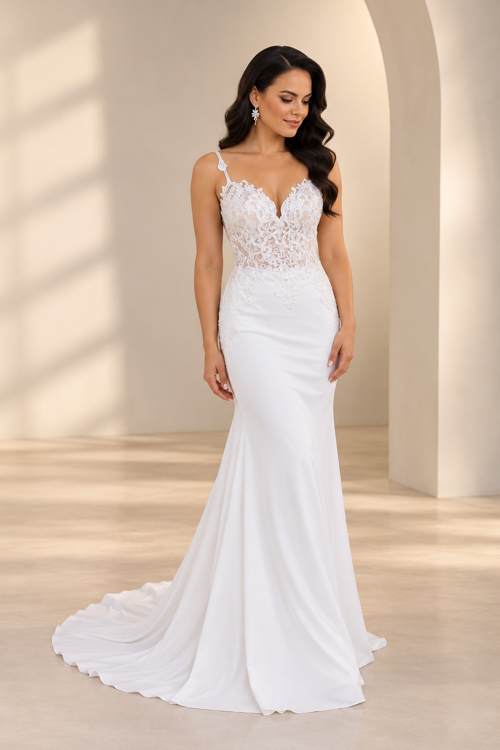 JOLENE A timeless mermaid wedding dress featuring a beautifully detailed lace bodice with a deep illusion V-neckline and delicate beaded straps. The sleek fitted silhouette flows effortlessly into a soft flared skirt and graceful lace-edged train