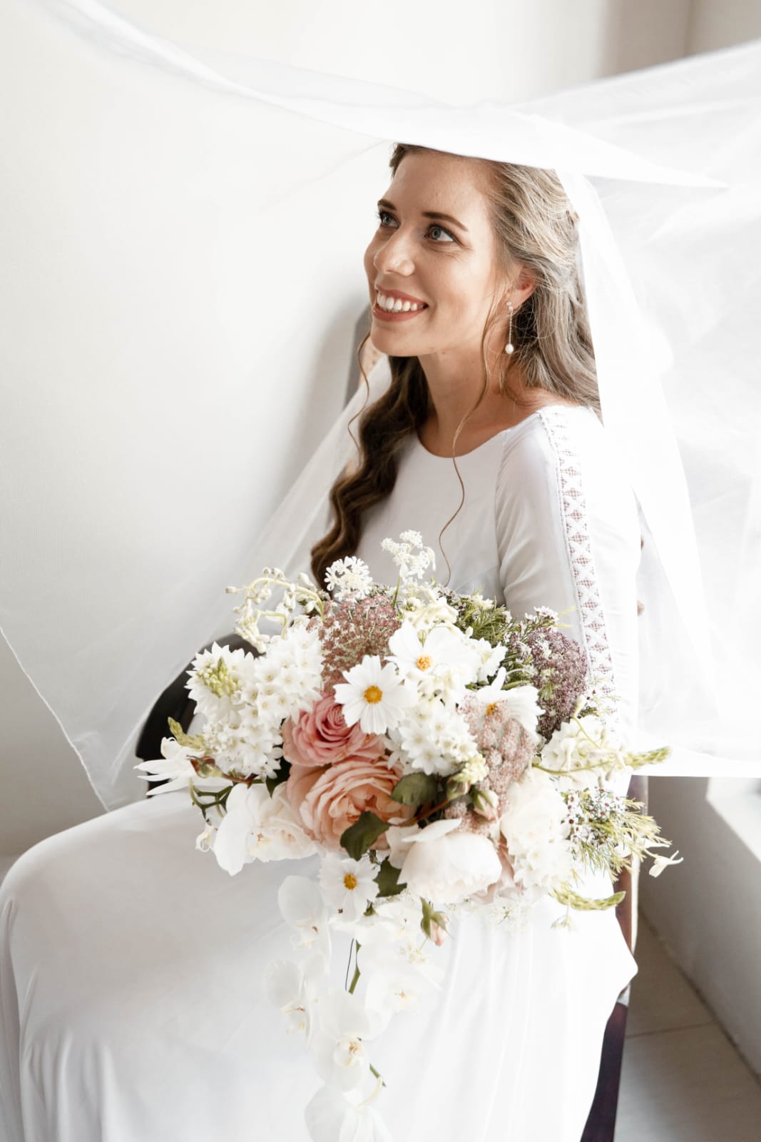 inge Boho-Inspired Chiffon & Lace A-Line Wedding Gown with Bishop Sleeves  The Inge gown is effortlessly romantic, perfect for the bride who dreams of soft movement, boho charm, and timeless lace detail. Crafted from flowing chiffon and delicate Chantilly lace, this dress radiates grace with every step.  ✨ Design Highlights: ✔ Bateau Neckline – A high, elegant neckline that frames the collarbone and exudes classic femininity. ✔ Sheer Chantilly Lace Back – A breathtaking illusion back with intricate lace detail and a delicate bridal button closure. ✔ Flowy A-Line Chiffon Skirt – Lightweight and soft, perfect for movement and comfort with a relaxed silhouette. ✔ Bishop Sleeves with Boho Lace – Long, airy sleeves gathered at the wrist with wide boho lace trim for a free-spirited yet refined look. ✔ Long Flowing Train – Adds ethereal beauty and soft bridal drama as you walk down the aisle.  💫 Customization Options: ✅ Custom sizing to ensure the perfect fit ✅ Option to adjust neckline or remove sleeves ✅ Available in soft white, ivory, or off-white chiffon and lace ✅ Add a matching veil with Chantilly lace trim  🌾 Inge is designed for the bride who wants to feel light, romantic, and a little whimsical—with textures and details that move with the breeze. 🌾  📞 Book your consultation or fitting today! 📧 info@bestersbridal.co.za | 📱 084 268 1354