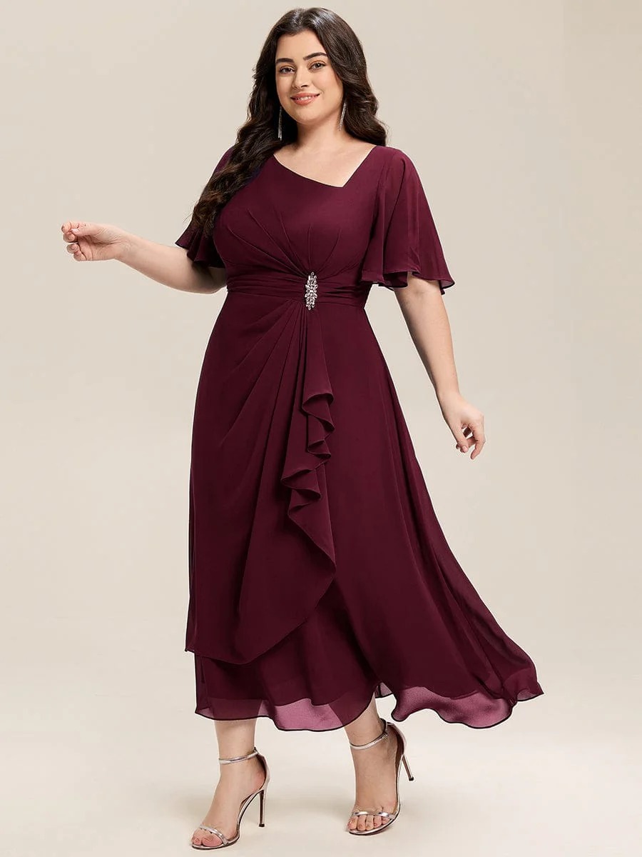 Lilou A beautifully pleated chiffon midi dress designed for plus-size elegance, featuring soft ruffle sleeves and a flattering flowy silhouette — perfect for any special celebration.  This dress is not currently in stock but is available to order.