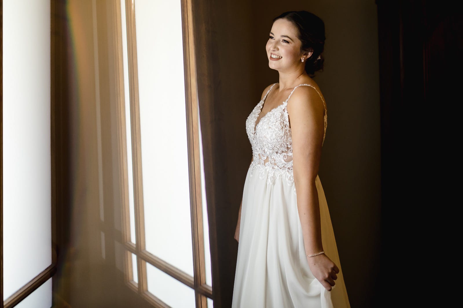 CARMEN An ethereal ivory wedding dress crafted from soft chiffon and delicate lace, perfect for a romantic, bohemian look. The sheer bodice is adorned with intricate lace details and complemented by thin beaded straps that add a touch of sparkle. The gown features a low back bodice, offering an alluring, elegant silhouette. Flowing effortlessly into a light and airy chiffon skirt, the dress cascades into a stunning long train, creating a graceful and dreamy movement with every step. Ideal for the bride seeking a blend of elegance and effortless charm