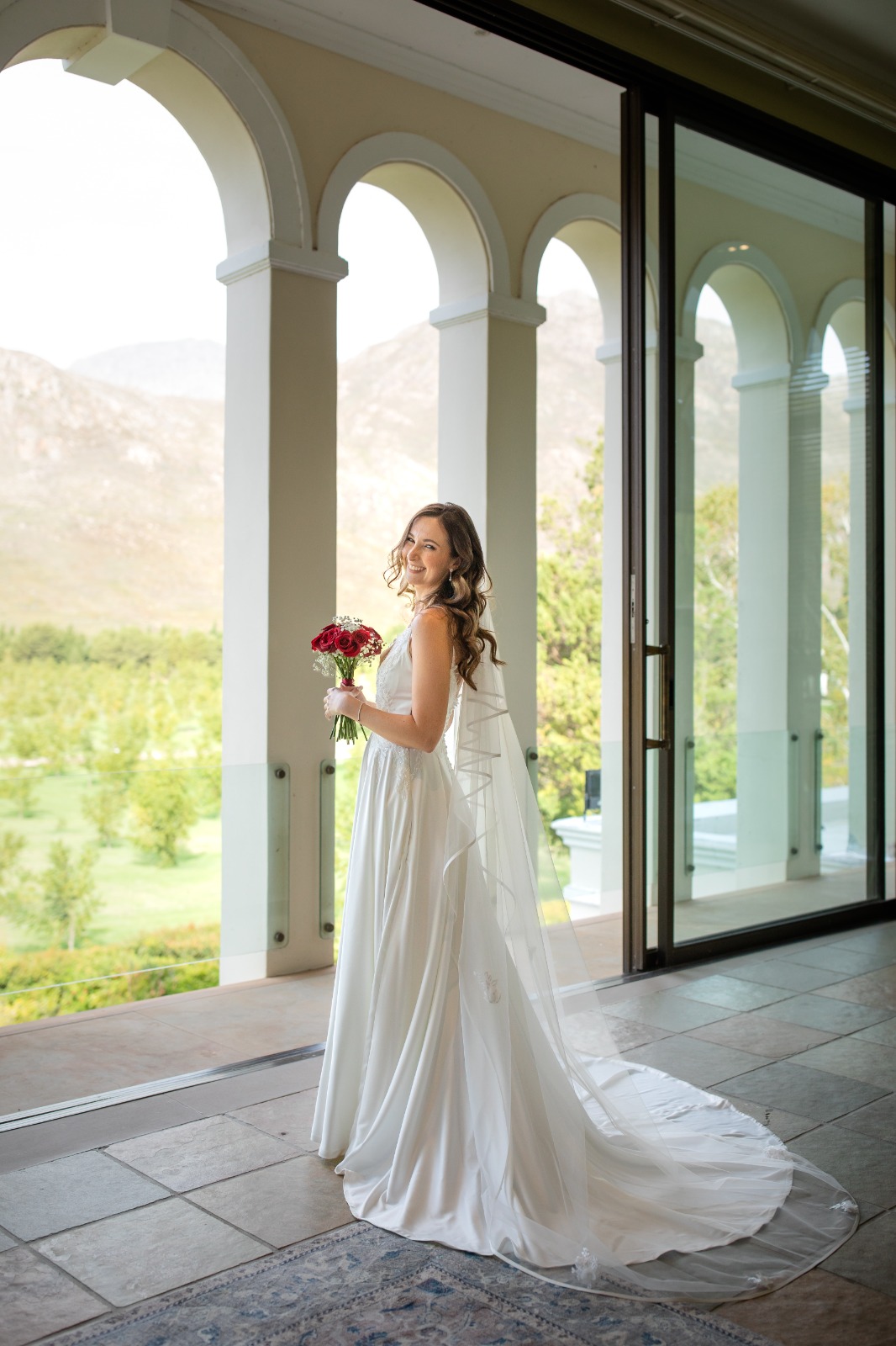 angie Satin A-Line Gown with Deep Plunge & Beaded Lace Details  The Angie gown is a striking combination of modern glamour and timeless elegance. With its dramatic deep V neckline and soft satin shine, this gown is designed to make a bold yet sophisticated bridal statement. Delicate beaded lace appliqués add texture and shimmer, while the full flare skirt ensures graceful movement down the aisle.  ✨ Design Highlights: ✔ Deep Plunge V-Neckline – A bold neckline softened with a nude tulle insert between the bust for comfort and coverage. ✔ Thin Beaded Lace Straps – Dainty yet detailed, offering a touch of sparkle while keeping the look light and refined. ✔ Embellished Lace Bodice – Intricately adorned with hand-placed beaded lace appliqués for a luxurious finish. ✔ Nude Tulle Side Inserts – Subtle inserts under the arms for breathability and a sleek silhouette. ✔ Full-Flare Satin A-Line Skirt with Pockets – A classic bridal shape with modern touches, designed for both style and practicality. ✔ Long Flowing Train – Creates a dramatic, elegant entrance. ✔ Button Closure at Back – A timeless bridal finish that adds polish and charm.  💫 Customization Options: ✅ Custom sizing for the perfect fit ✅ Option to raise or soften the neckline ✅ Available in soft white or ivory satin ✅ Add a matching veil or lace bolero for styling versatility  ✨ Angie is perfect for the bride who wants shine, structure, and a touch of sparkle—wrapped in a silhouette that flatters and flows. ✨  📞 Book your consultation or fitting now! 📧 info@bestersbridal.co.za | 📱 084 268 1354  Satin A-Line • Deep V Neck • Beaded Lace Straps & Bodice • Pockets • Long Train • Button Closure