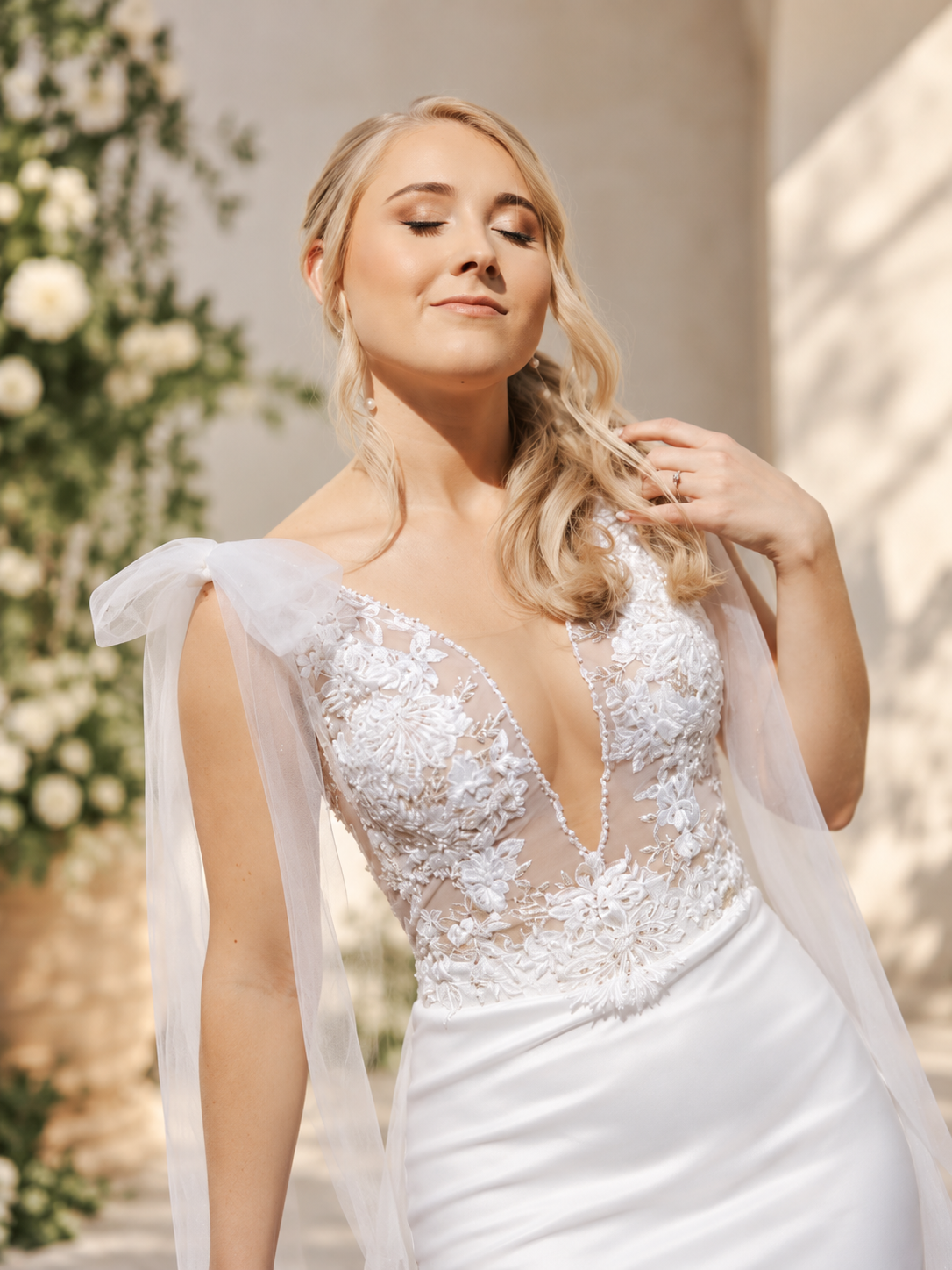 MARIZAAN An elegant off-white wedding dress featuring a delicate lace bodice with sheer lace sleeves, paired with a sleek crepe sheath skirt and a beautiful lace train.