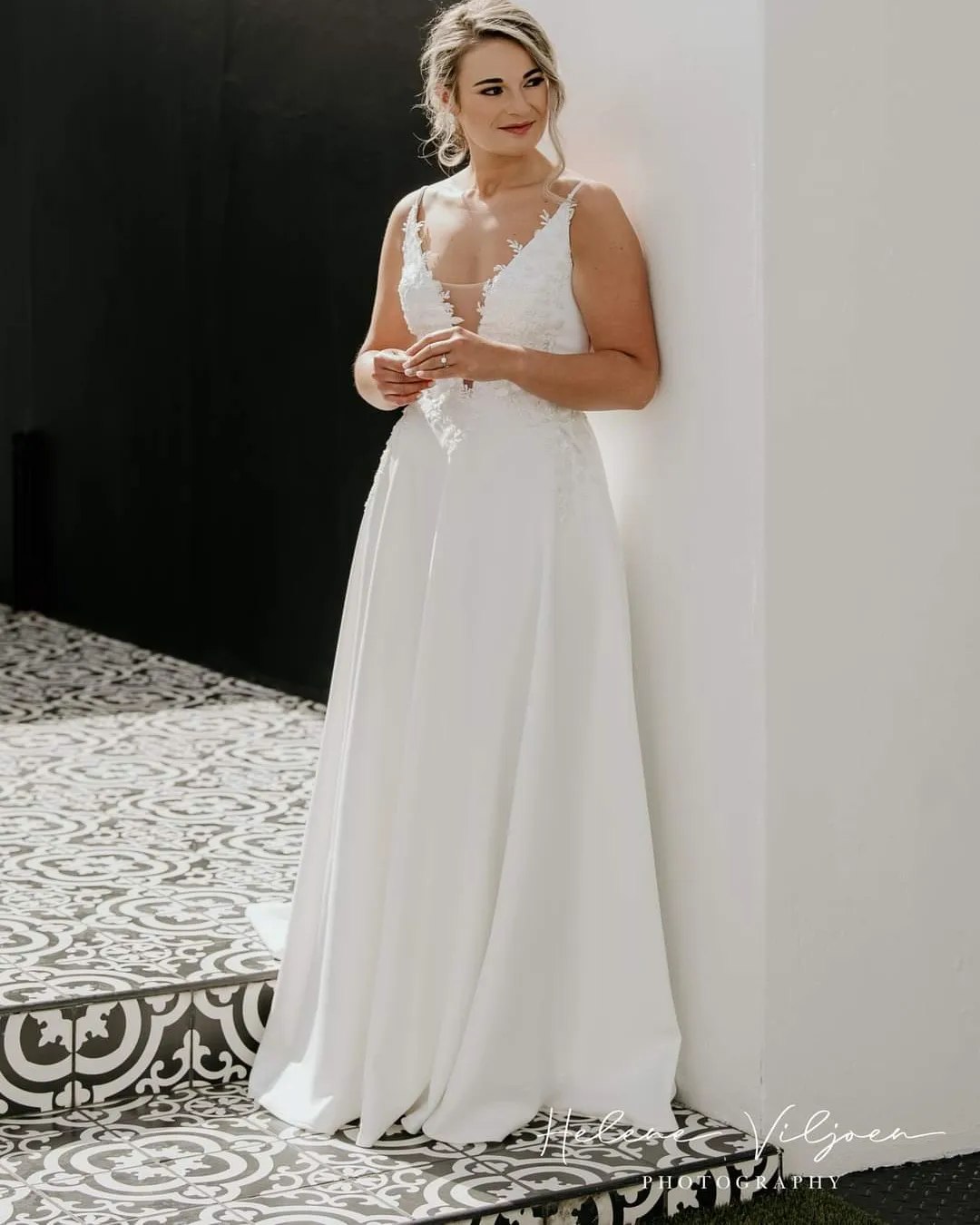 ALMA An effortlessly elegant A-line wedding gown designed to make a statement. The dress features a daring deep plunge bustline with a soft tulle insert between the bust and under the arms, adding a touch of allure while providing subtle coverage. The full-flare crepe skirt flows beautifully, complete with convenient side pockets for a modern, practical touch. A low open back enhances the gown's sophisticated charm, while a short train adds just the right amount of drama. Perfect for the contemporary bride seeking refined simplicity with a hint of boldness.