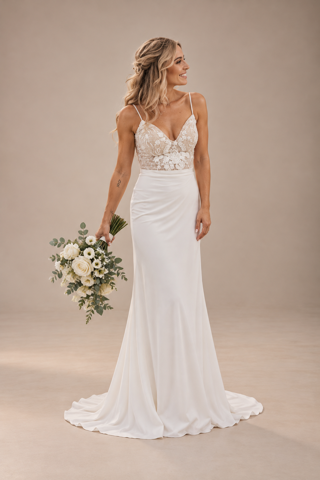 JOLENE A timeless mermaid wedding dress featuring a beautifully detailed lace bodice with a deep illusion V-neckline and delicate beaded straps. The sleek fitted silhouette flows effortlessly into a soft flared skirt and graceful lace-edged train