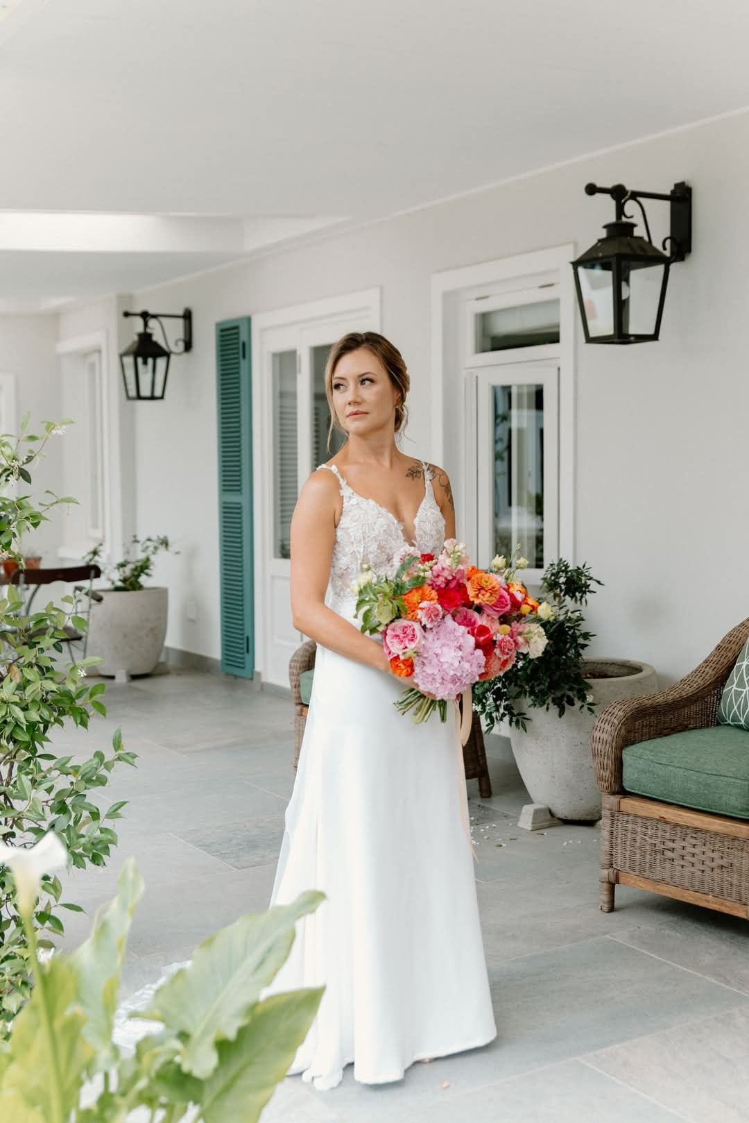 Naidene An elegant off-white sheath wedding dress crafted from a blend of lace and crepe, adorned with exquisite 3D floral and leaf lace appliqués. The dress features a stunning low open back, delicate thin straps, and is finished with a graceful lace-trimmed train, adding a touch of romantic charm.